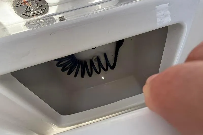 Slide: The Image of Storage compartment on a 2022 Tidewater 272 LXF boat, featuring a coiled hose. - 13