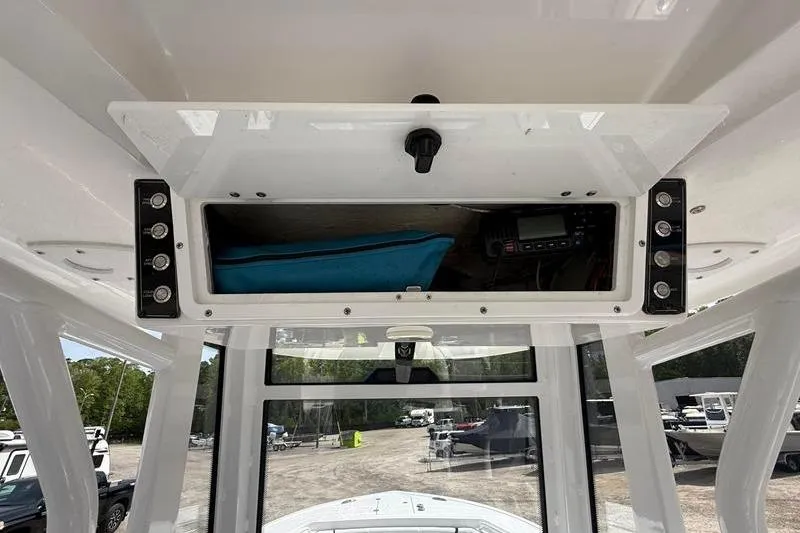 Slide: The Image of 2022 Tidewater 272 LXF boat console storage with electronic equipment and blue cover. - 23