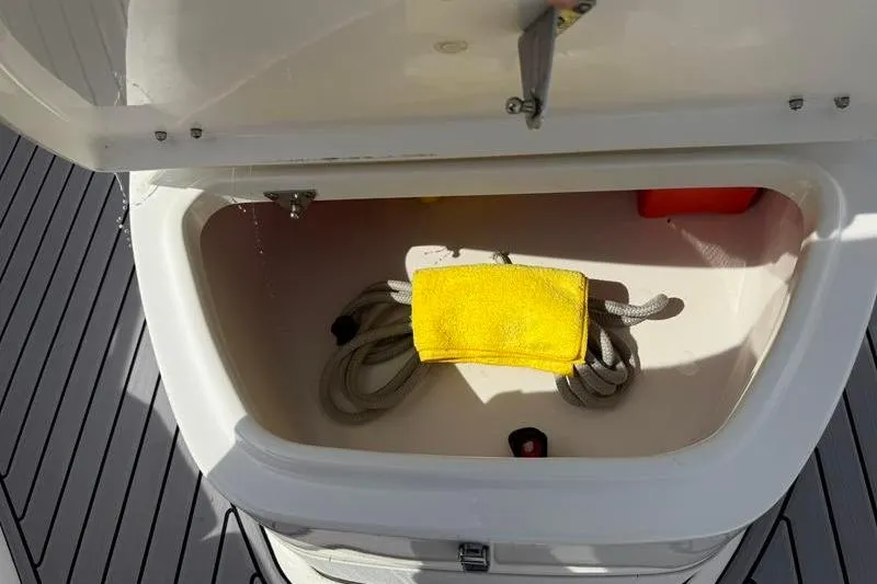 Slide: The Image of Open storage compartment on 2022 Tidewater 272 LXF boat with rope and yellow cloth. - 32