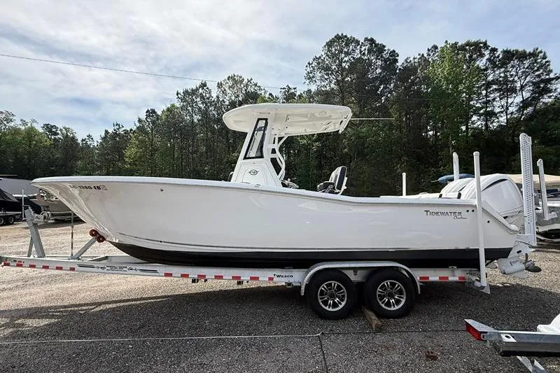 Slide: The Image of 2022 Tidewater 272 LXF boat on trailer, parked outdoors with trees in background. - 5