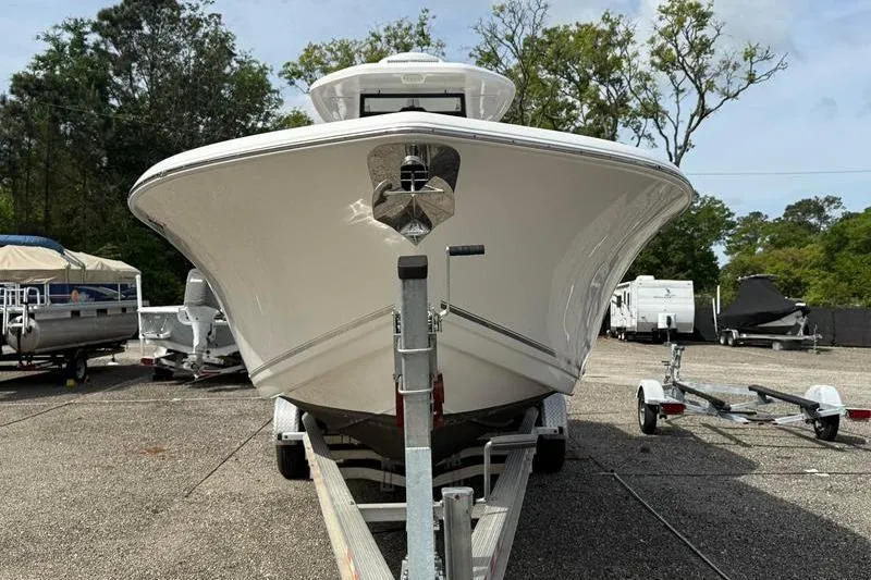 Slide: The Image of 2022 Tidewater 272 LXF boat on trailer, parked outdoors with trees in background. - 7