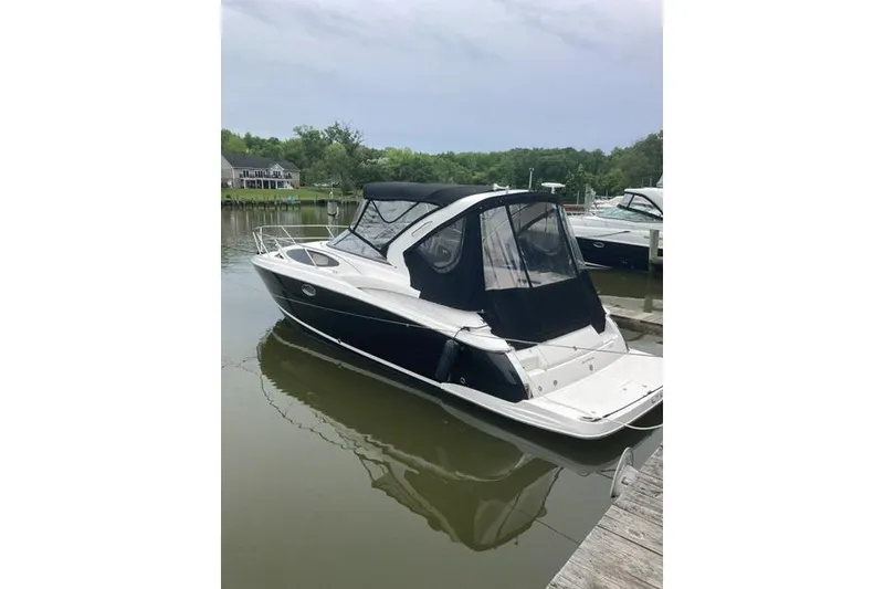 Slide: The Image of 2013 Regal 35 Express Cruiser docked on calm water, featuring sleek design and black canopy. - 5