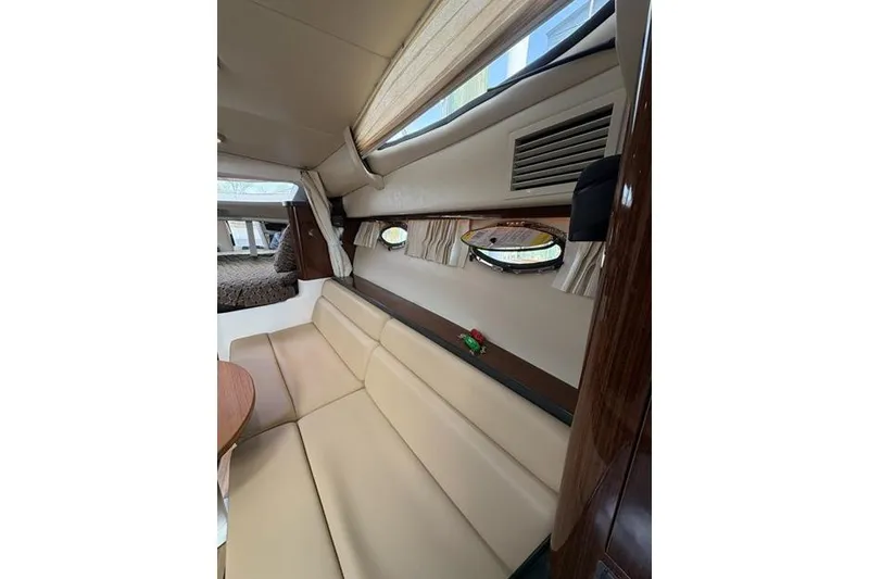 Slide: The Image of Interior of 2013 Regal 35 Express Cruiser with beige seating and porthole windows. - 54