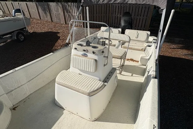 Slide: The Image of 2014 Carolina Skiff 218 DLV boat with seating and console, parked outdoors. - 12