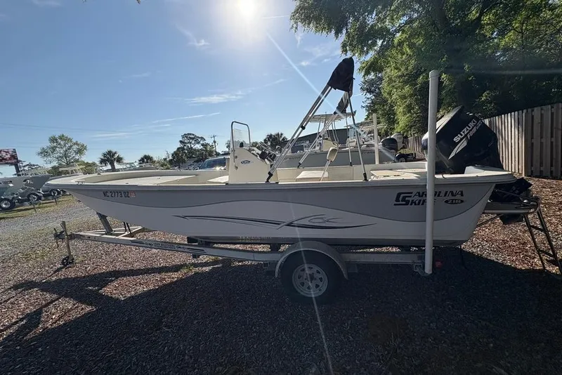 Slide: The Image of 2014 Carolina Skiff 218 DLV boat on trailer, parked outdoors under sunlight. - 6