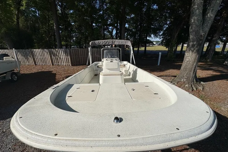 Slide: The Image of 2014 Carolina Skiff 218 DLV boat parked outdoors, surrounded by trees and fencing. - 9