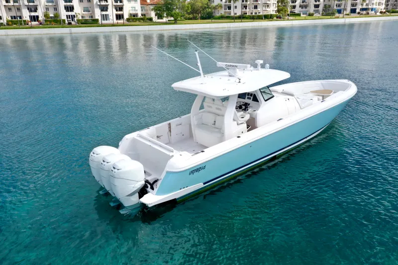 Slide: The Image of 2022 Intrepid 407 Nomad SE boat on clear blue water near waterfront buildings. - 2