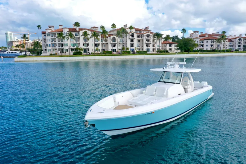 Slide: The Image of 2022 Intrepid 407 Nomad SE boat on calm water near luxury waterfront buildings. - 5