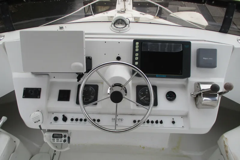 Slide: The Image of 1997 Mainship 350 Trawler helm with steering wheel, gauges, and navigation equipment. - 13