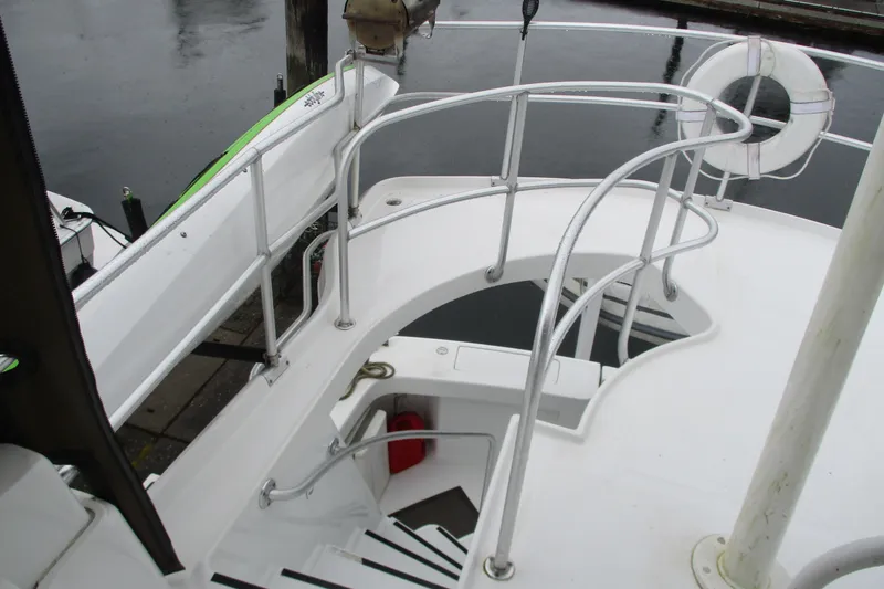Slide: The Image of 1997 Mainship 350 Trawler deck with railing and life preserver, docked by the water. - 18