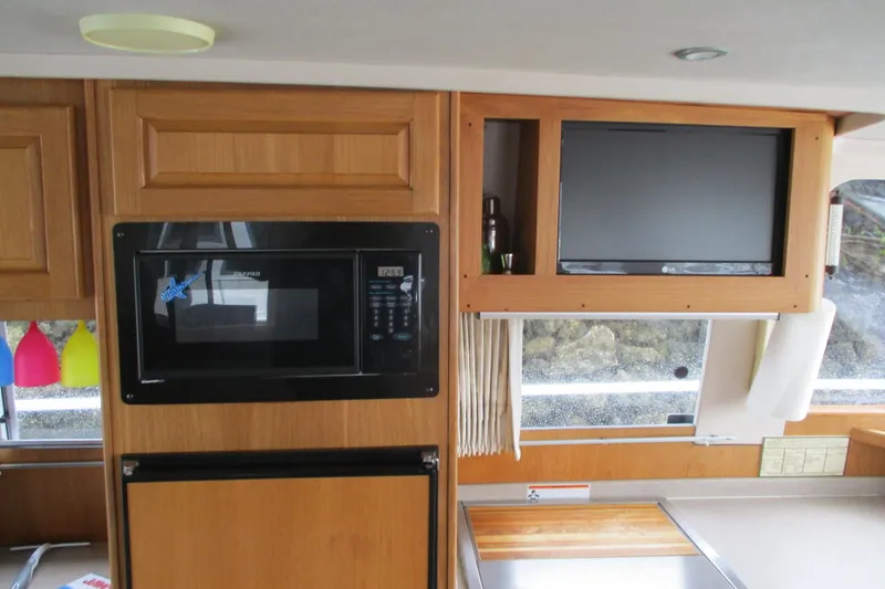Slide: The Image of Interior of 1997 Mainship 350 Trawler with microwave, TV, and wooden cabinetry. - 27