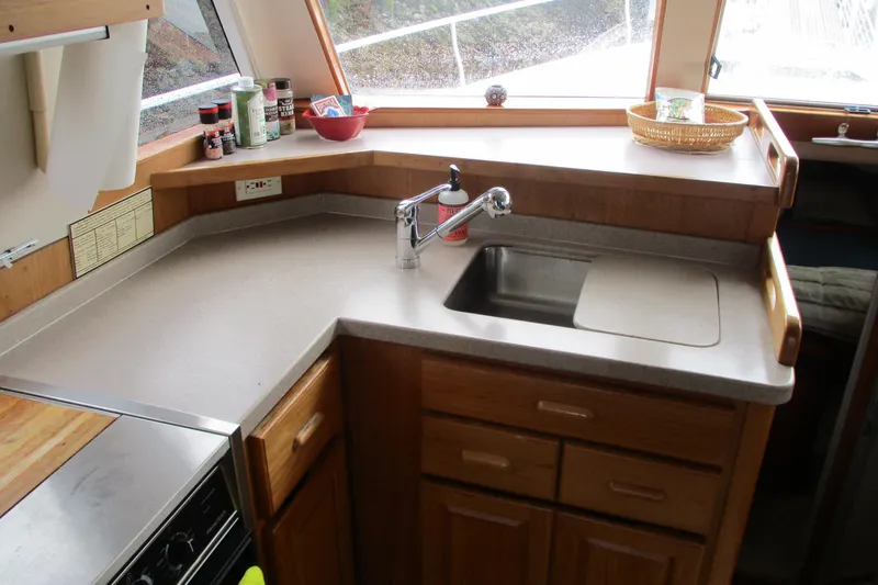 Slide: The Image of 1997 Mainship 350 Trawler kitchen with sink, countertop, and wooden cabinetry. - 30