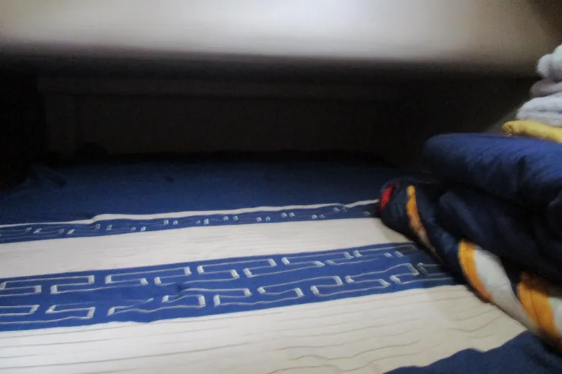 Slide: The Image of Cozy sleeping area in a 1997 Mainship 350 Trawler with blue patterned bedding. - 38