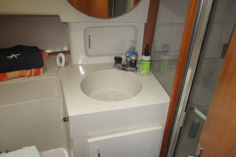 Slide: The Image of Bathroom sink area in a 1997 Mainship 350 Trawler, featuring toiletries and wooden cabinetry. - 39