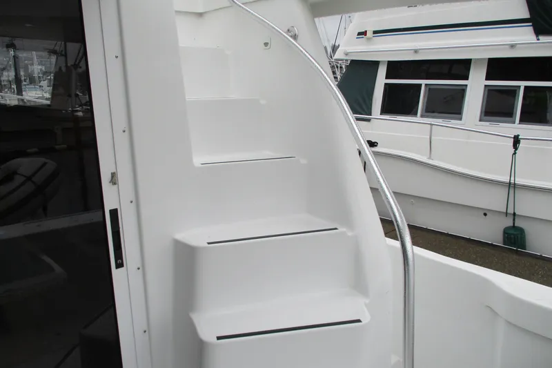 Slide: The Image of Staircase on a 1997 Mainship 350 Trawler, featuring sleek white design and metal railing. - 54