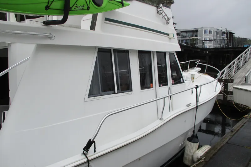 Slide: The Image of 1997 Mainship 350 Trawler docked, featuring sleek white exterior and windows. - 61