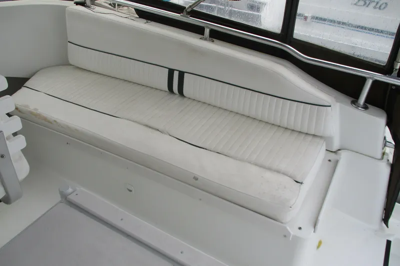 Slide: The Image of White seating area on a 1997 Mainship 350 Trawler boat, featuring cushioned bench. - 15