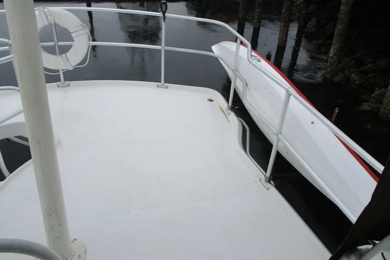Slide: The Image of 1997 Mainship 350 Trawler deck with railing and lifebuoy, docked near water. - 17