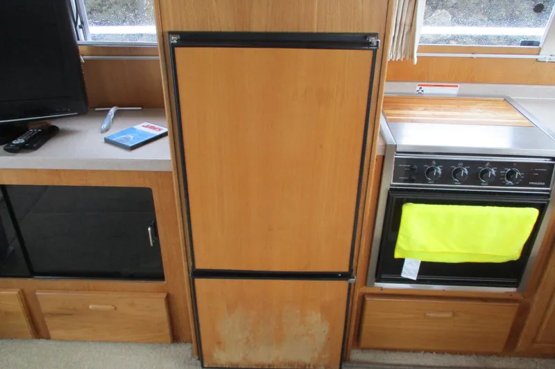 Slide: The Image of 1997 Mainship 350 Trawler kitchen with wooden cabinetry, stove, and refrigerator. - 28