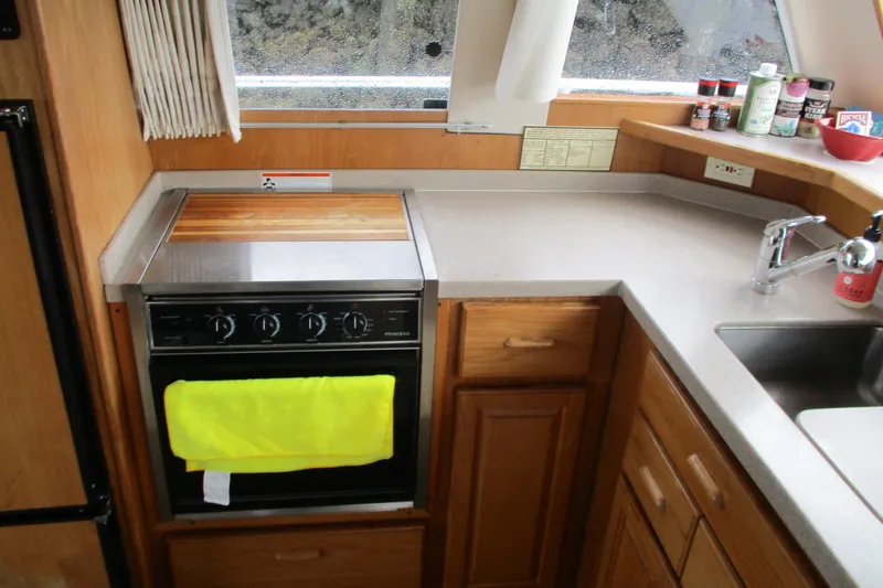 Slide: The Image of 1997 Mainship 350 Trawler kitchen with stove, sink, and wooden cabinetry. - 29