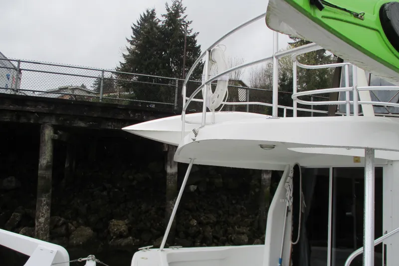 Slide: The Image of 1997 Mainship 350 Trawler docked near a wooden pier, featuring upper deck and railing. - 58