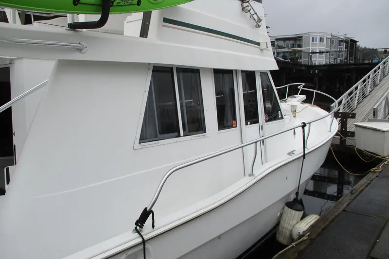 Slide: The Image of 1997 Mainship 350 Trawler docked, showcasing sleek white exterior and windows. - 60