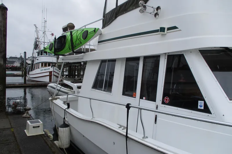 Slide: The Image of 1997 Mainship 350 Trawler docked with green kayak on top, overcast day. - 9