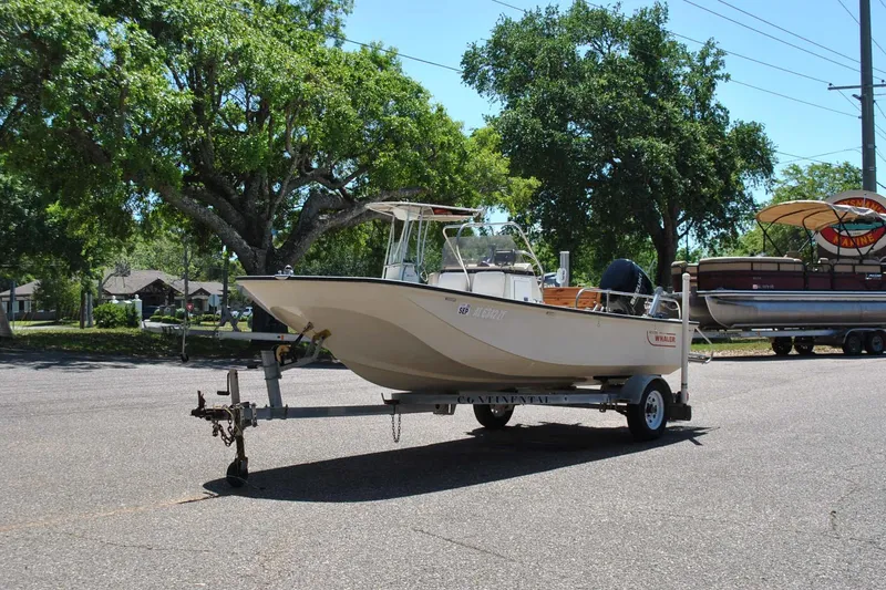 Slide: The Image of 1992 Boston Whaler 17 Montauk boat on trailer, parked outdoors under trees. - 10