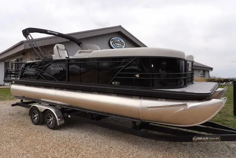 The Image of 2026 Sylvan X5 CLZ pontoon boat on trailer, parked outside a building. - 1