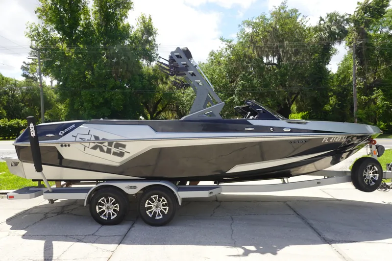 Slide: The Image of 2019 Axis T23 boat on trailer, parked outdoors with lush greenery background. - 3
