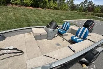 Slide: The Image of 2005 Tracker Tournament V-18 All Fish boat with striped seats and motor, parked outdoors. - 4