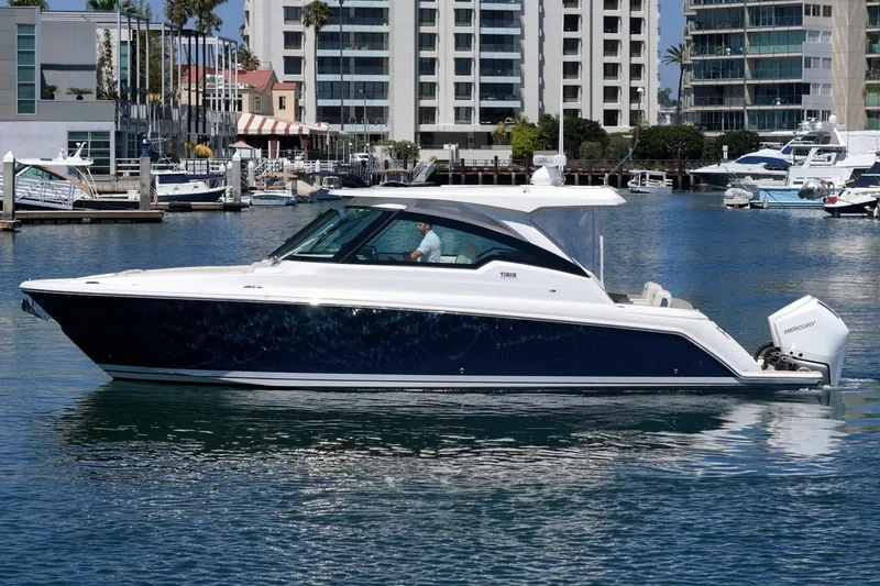 Slide: The Image of 2026 Tiara Yachts 34 LX cruising in a marina with modern buildings in the background. - 7