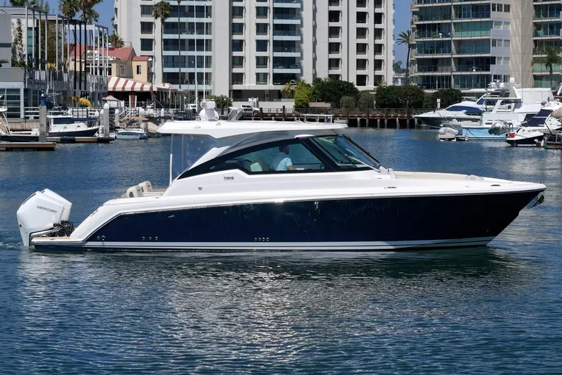 Slide: The Image of 2026 Tiara Yachts 34 LX cruising in a marina with modern buildings in the background. - 8