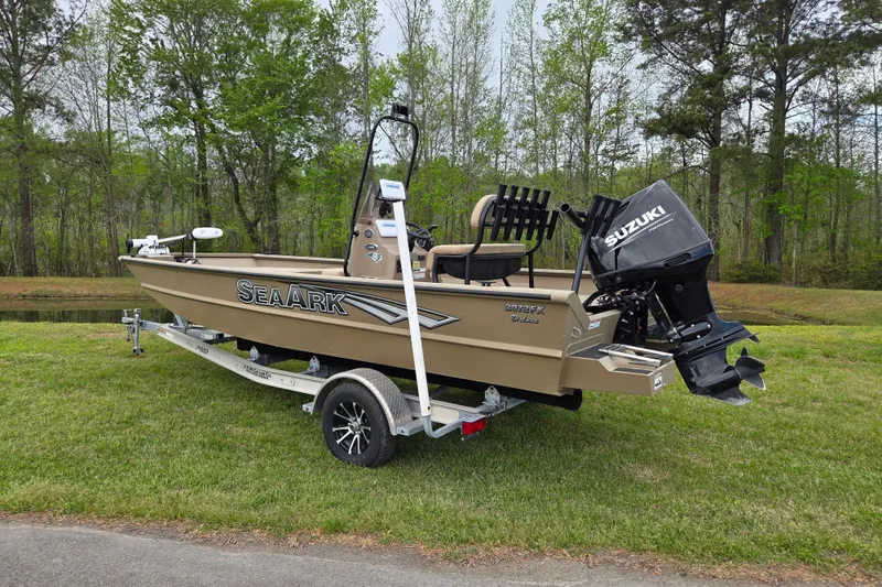 Slide: The Image of 2024 SeaArk 2072 FX boat with Suzuki motor on trailer, parked on grass. - 2