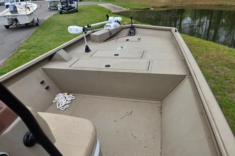 Slide: The Image of 2024 SeaArk 2072 FX boat interior with storage compartments and trolling motor by a pond. - 7