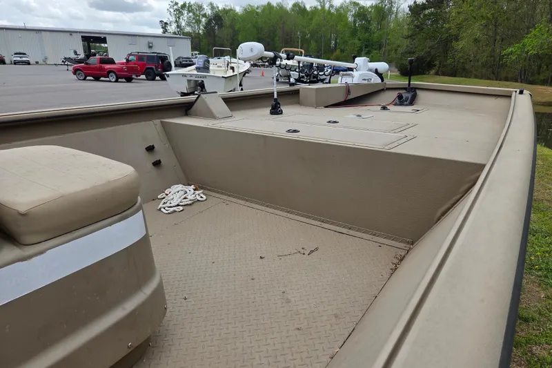 Slide: The Image of 2024 SeaArk 2072 FX boat interior with seating and storage, parked outdoors. - 8