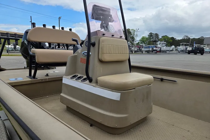 Slide: The Image of 2024 SeaArk 2072 FX boat interior with seating and console, parked outdoors. - 9