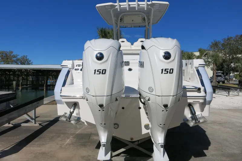 Slide: The Image of 2026 Robalo R250 Center Console with twin 150 horsepower engines, docked under clear blue sky. - 4