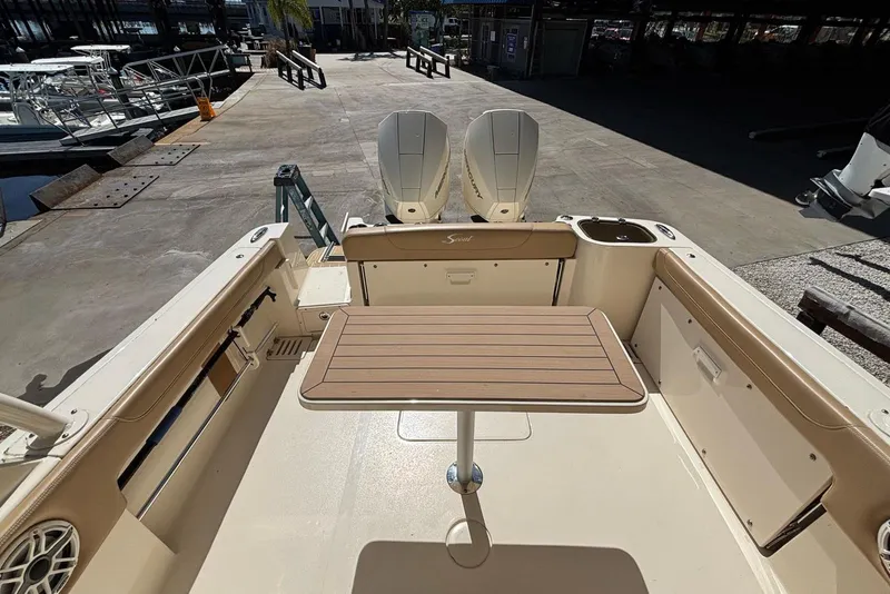 Slide: The Image of 2024 Scout 255 Dorado boat interior with table and dual engines at dock. - 13