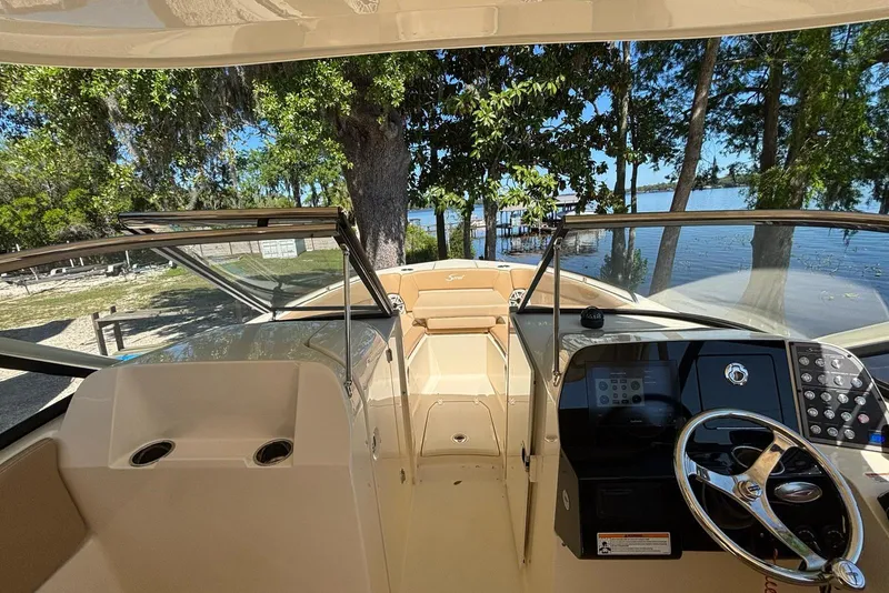 Slide: The Image of 2024 Scout 255 Dorado boat interior with steering wheel, dashboard, and lake view. - 24