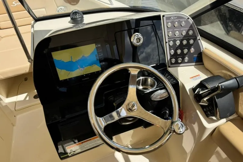 Slide: The Image of 2024 Scout 255 Dorado boat dashboard with steering wheel and navigation display. - 26