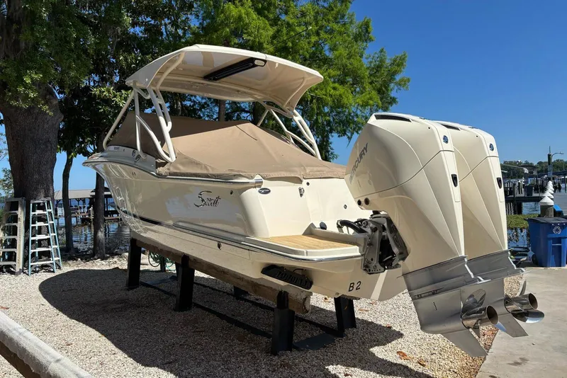 Slide: The Image of 2024 Scout 255 Dorado boat with dual Mercury engines, docked under a sunny sky. - 3