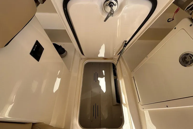 Slide: The Image of 2024 Scout 255 Dorado boat interior storage compartment with open hatch and beige seating. - 32