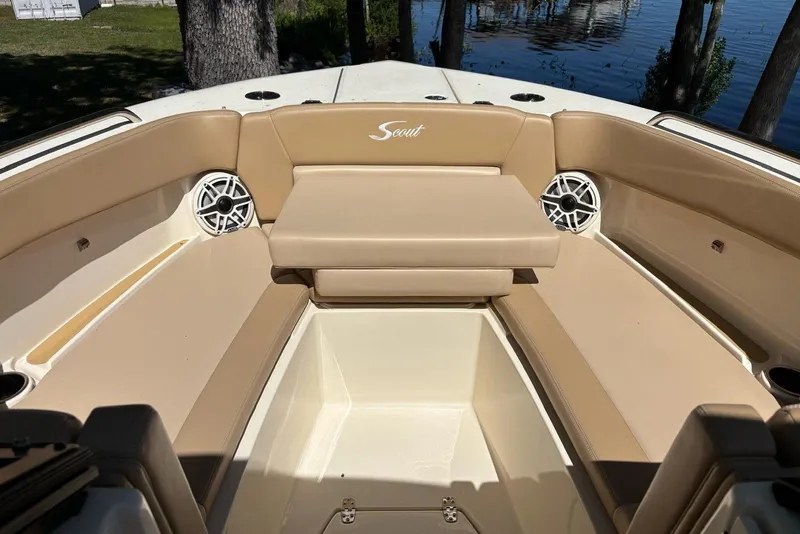 Slide: The Image of 2024 Scout 255 Dorado boat interior with tan seating and speakers, near water. - 33