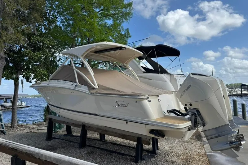 Slide: The Image of 2024 Scout 255 Dorado boat with Mercury engine docked by a lake. - 4