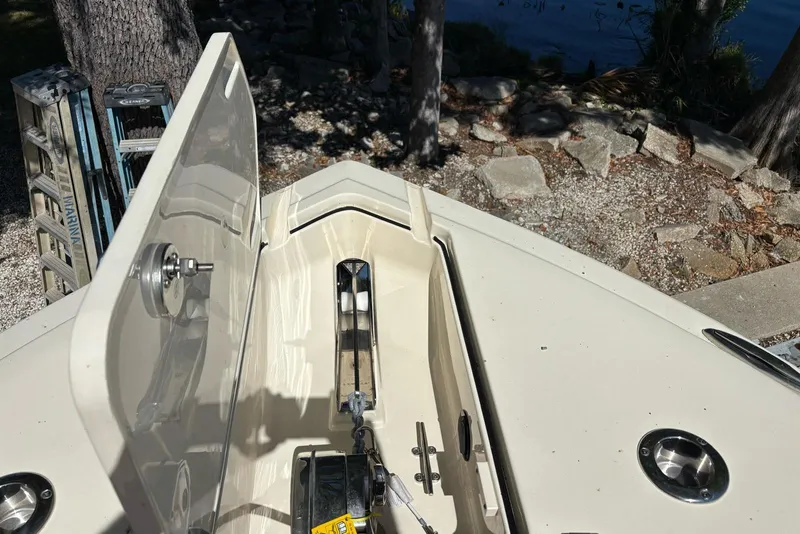 Slide: The Image of 2024 Scout 255 Dorado boat anchor compartment, open lid, rocky shoreline background. - 44