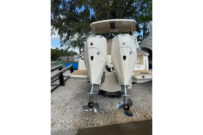 Slide: The Image of 2024 Scout 255 Dorado boat with dual outboard engines, parked on gravel. - 46