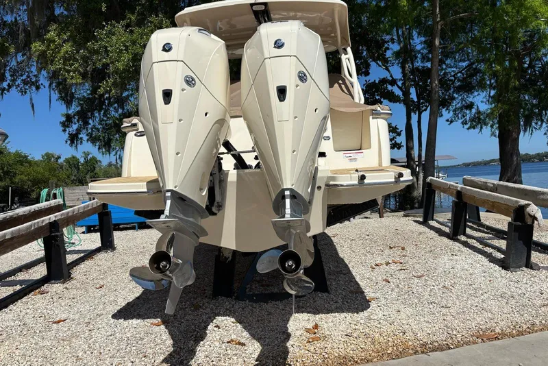 Slide: The Image of 2024 Scout 255 Dorado boat with dual outboard engines on display by the water. - 7