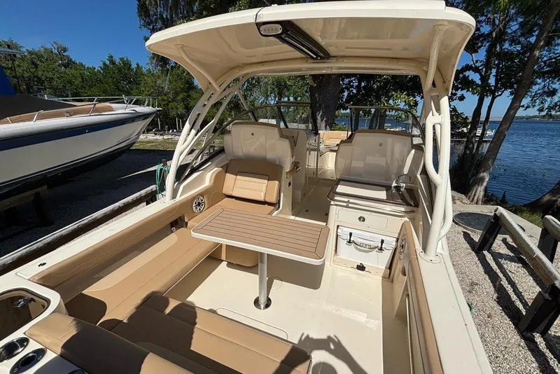 Slide: The Image of 2024 Scout 255 Dorado boat interior with seating and table, docked by a scenic lake. - 9