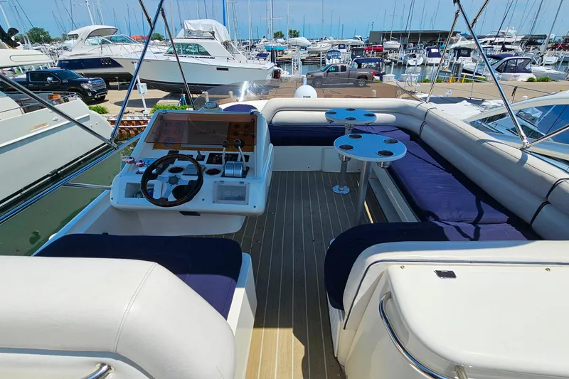 Slide: The Image of Flybridge of 1998 Sunseeker Manhattan 62 yacht with seating and helm, docked at marina. - 54